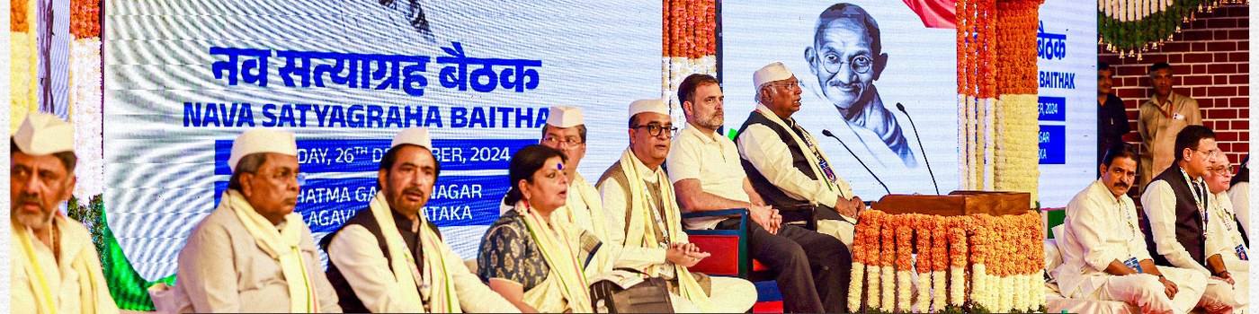 Rahul Gandhi and Congress leaders on stage at the Nava Satyagraha Baithak in Belgaum, with a portrait of Mahatma Gandhi behind them