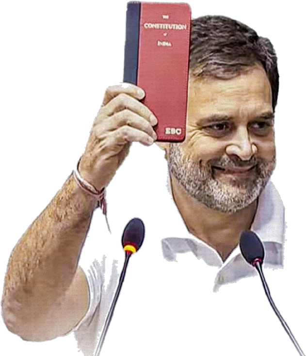 Rahul Gandhi smiling and holding up a red copy of the Constitution of India above a pair of microphones