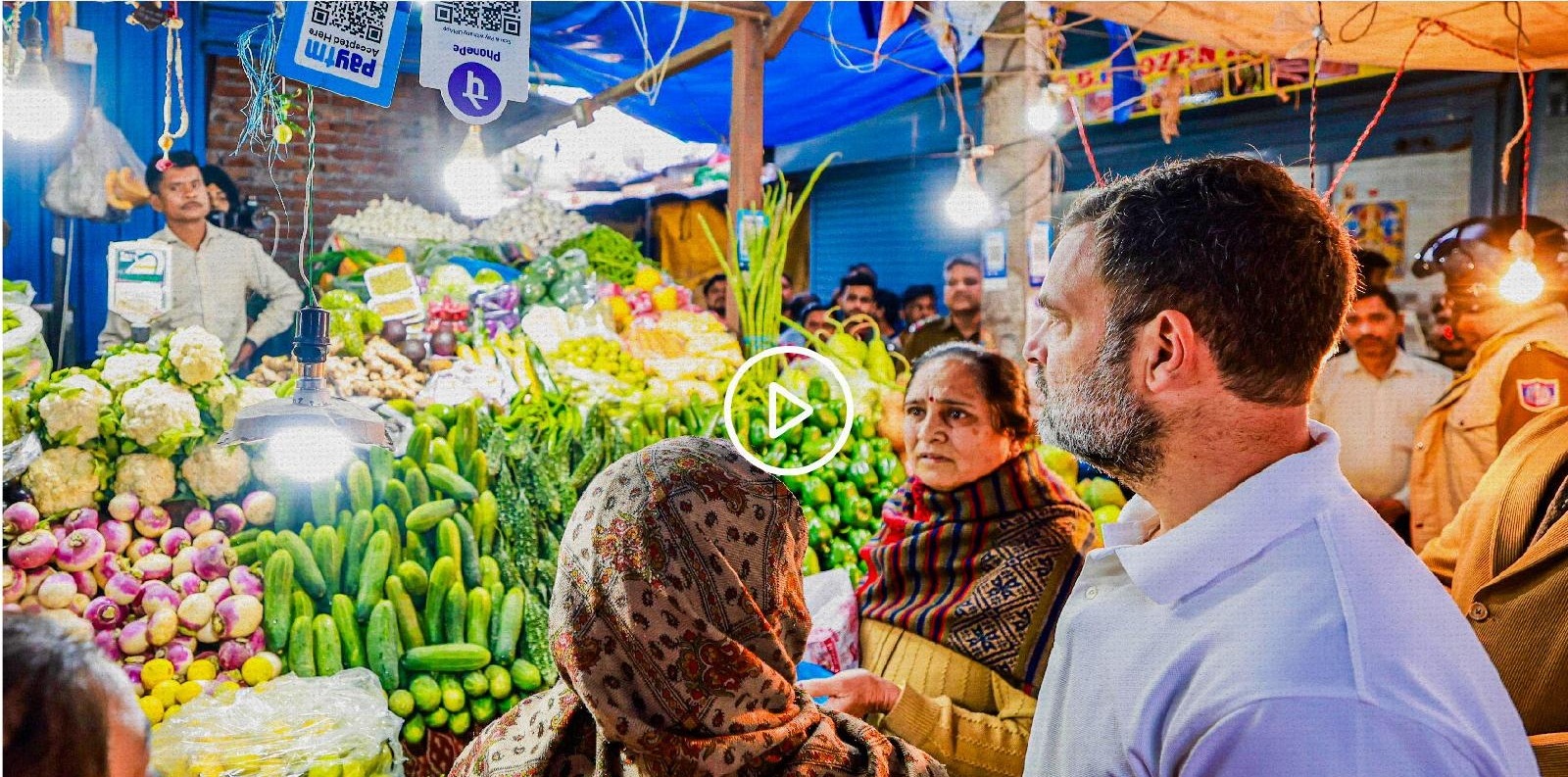 Rahul Gandhi standing in a busy vegetable market in Delhi, talking with vendors and customers amid fresh produce